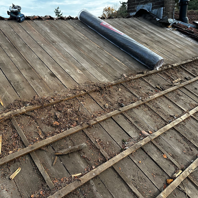 Vakkundige dakdekkers bezig met het vervangen van dakpannen op een woning